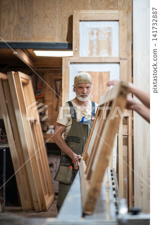 Professional man carpenter working in restoration workshop on vintage wooden door reconstruction Professional man carpenter working in restoration workshop on vintage wooden door reconstruction 141732887