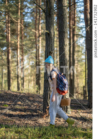 Seasonal foraging and spending time outdoors, woman backpacker searching for edibles in woods. Seasonal foraging and spending time outdoors, woman backpacker searching for edibles in woods. 141732902