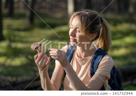 Seasonal food ingredients preparations and hobby, woman forager picking up mushrooms in forest. Seasonal food ingredients preparations and hobby, woman forager picking up mushrooms in forest. 141732944