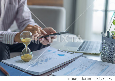 Professional Reviewing Income Tax Report and Expenses in Office with Hourglass on Table. Time Management Concept. 141732969