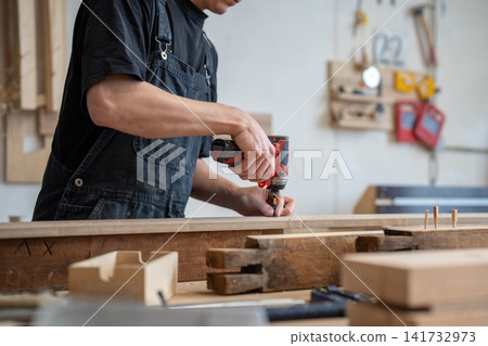 Craftsman technician working in restoration workshop, using professional cordless impact driver tool Craftsman technician working in restoration workshop, using professional cordless impact driver tool 141732973