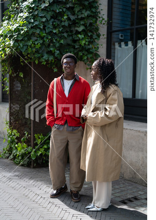 Relaxed african american couple man and woman students meeting outdoors after lessons for chat. Relaxed african american couple man and woman students meeting outdoors after lessons for chat. 141732974