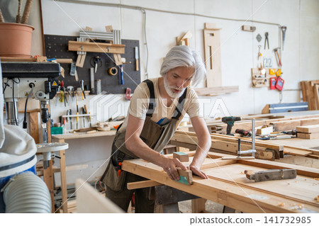 Professional craftsman working on restoration of antique wooden door at workbench in carpentry Professional craftsman working on restoration of antique wooden door at workbench in carpentry 141732985