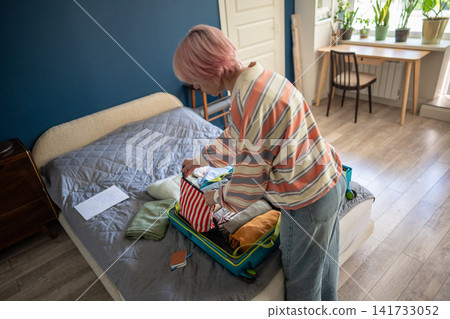 Woman traveler finishing packing personal belongings in suitcase for planned vacation journey. Woman traveler finishing packing personal belongings in suitcase for planned vacation journey. 141733052