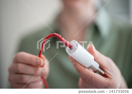 Woman demonstrating smartphone charging adapter with damaged broken cable sticking out of usb port Woman demonstrating smartphone charging adapter with damaged broken cable sticking out of usb port 141733056