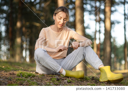 Solitude, inner peace and outdoor activity, positive woman sits on forest ground enjoys quiet moment Solitude, inner peace and outdoor activity, positive woman sits on forest ground enjoys quiet moment 141733080
