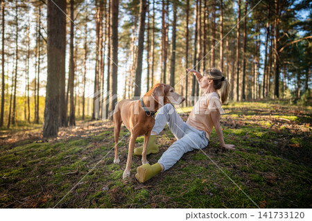 Relaxed female hiker sitting on ground basking in sun observing woodlands, harmony and inner peace. Relaxed female hiker sitting on ground basking in sun observing woodlands, harmony and inner peace. 141733120
