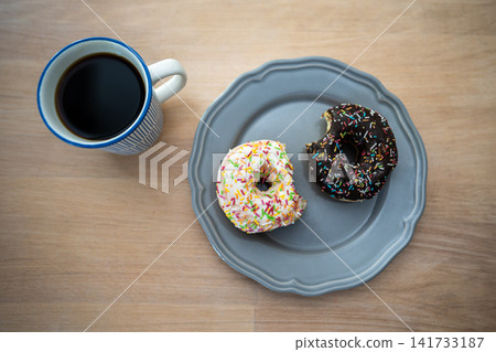 Mug of coffee and portion of glazed doughnuts on plate showcasing sugar addiction and indulgence. 141733187