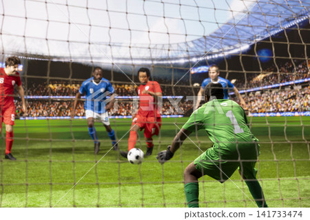 Selective focus of attacker hitting ball close to net and goalie, red player controlling ball and dribbling opponents inside penalty area. Goalkeeper in green defending goal post. Selective focus of attacker hitting ball close to net and goalie, red player controlling ball and dribbling opponents inside penalty area. Goalkeeper in green defending goal post. 141733474