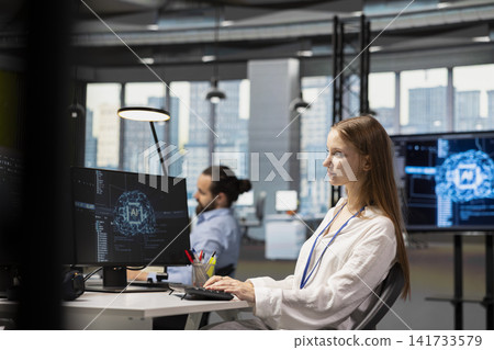 Female developer in modern office leveraging AI tools to automate routine coding tasks. Young programmer using artificial intelligence to accelerate software feature development Female developer in modern office leveraging AI tools to automate routine coding tasks. Young programmer using artificial intelligence to accelerate software feature development 141733579