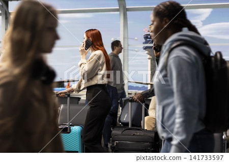 Talking on phone, busy airport and girl asking family to pick her up after plane landing, arriving home for holidays. Doing telephone call, international voyage and woman walking in departure terminal Talking on phone, busy airport and girl asking family to pick her up after plane landing, arriving home for holidays. Doing telephone call, international voyage and woman walking in departure terminal 141733597