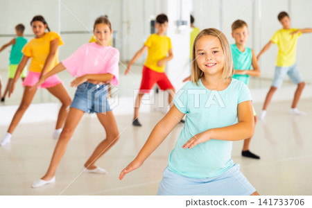 Cheerful preteen girl learning energetic dance in choreography class Cheerful preteen girl learning energetic dance in choreography class 141733706