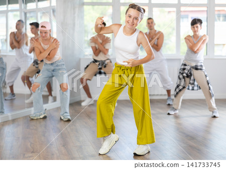 Active teenagers practicing hip hop dance in training hall during group dancing classes Active teenagers practicing hip hop dance in training hall during group dancing classes 141733745