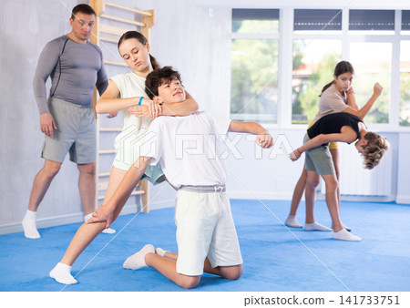 Preteen children, boy and girl, working in pair mastering new self defense moves at gym Preteen children, boy and girl, working in pair mastering new self defense moves at gym 141733751