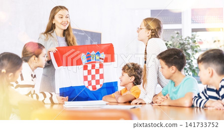 Female teacher working with students in school class, talking about national flag of Croatia at history lesson Female teacher working with students in school class, talking about national flag of Croatia at history lesson 141733752