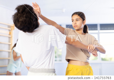 Boy and girl train to perform works out blow to jaw at opponent, while learning self-defense Boy and girl train to perform works out blow to jaw at opponent, while learning self-defense 141733763