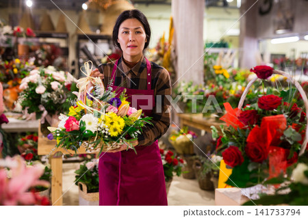 Portrait of an asian florist woman standing in a shop with flowers Portrait of an asian florist woman standing in a shop with flowers 141733794