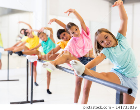 Cheerful girl working near ballet barre during group choreography class 141733839