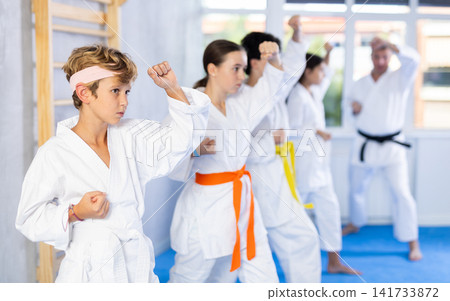 Children students repeat position and perform sequence of punches and painful techniques kata Children students repeat position and perform sequence of punches and painful techniques kata 141733872