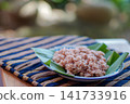 Traditional Indonesian brown rice served on banana leaf plate with natural lighting. Healthy Asian food, whole grain rice, authentic Southeast Asian cuisine. 141733916
