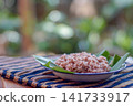 Traditional Indonesian brown rice served on banana leaf plate with natural lighting. Healthy Asian food, whole grain rice, authentic Southeast Asian cuisine. 141733917