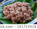 Close up of brown rice texture served on banana leaf. Healthy whole grain Asian food ingredient with natural daylight. 141733918