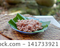 Traditional Indonesian brown rice served on banana leaf plate with natural lighting. Healthy Asian food, whole grain rice, authentic Southeast Asian cuisine. 141733921