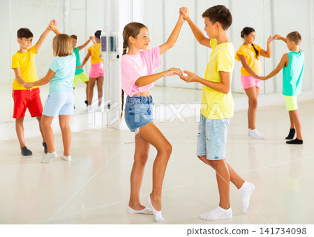 Sporty preteen children learning to dance vigorous jive in pairs Sporty preteen children learning to dance vigorous jive in pairs 141734098