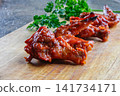 Close-up of spicy barbecue chicken wings on wooden board. Popular comfort food and bar snack concept. 141734171