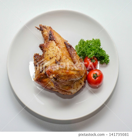 Roasted chicken breast quarter served on white plate with parsley and cherry tomato. Roasted chicken breast quarter served on white plate with parsley and cherry tomato. 141735081
