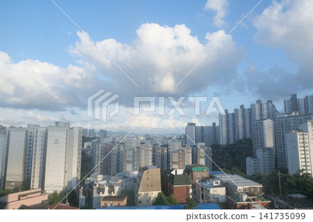 Urban apartment complex under a blue sky and fluffy white clouds 141735099