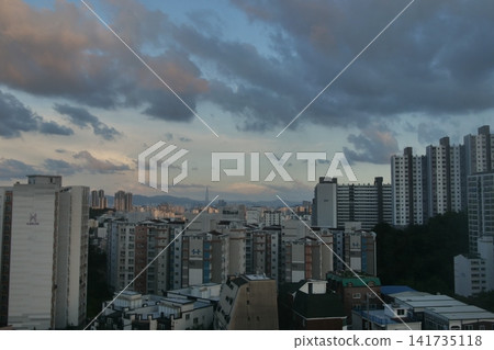 Urban apartment complex under a blue sky and fluffy white clouds Urban apartment complex under a blue sky and fluffy white clouds 141735118