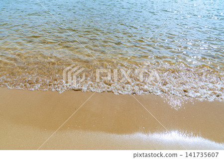 Background image of gentle waves lapping against the shoreline and sandy beach. Background image of gentle waves lapping against the shoreline and sandy beach. 141735607