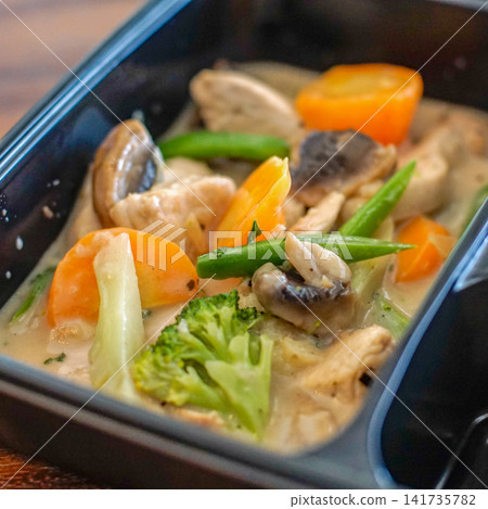 Close-up of creamy chicken stew with vegetables in a takeaway container. Food texture and comfort meal concept. Close-up of creamy chicken stew with vegetables in a takeaway container. Food texture and comfort meal concept. 141735782