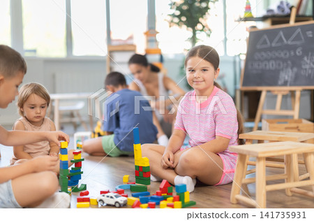 Little children sitting on floor together and playing educational games and toys at classes for kids Little children sitting on floor together and playing educational games and toys at classes for kids 141735931