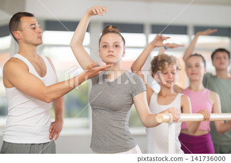 Girls and boys in ballet class perform third position under male teacher guidance. Girls and boys in ballet class perform third position under male teacher guidance. 141736000