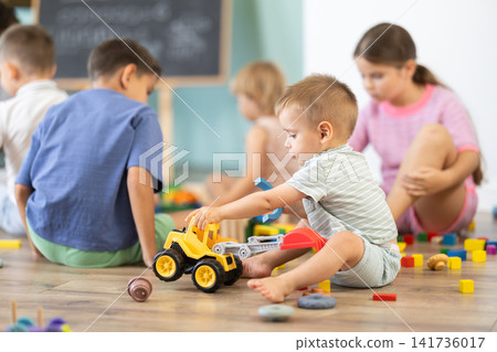 Baby boy playing with wooden toys on floor in kindergarten 141736017
