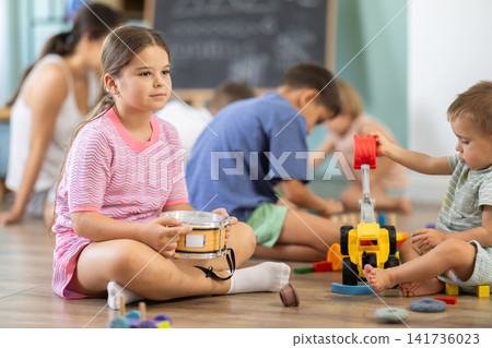 Little girl playing with wooden blocks on floor inside playroom Little girl playing with wooden blocks on floor inside playroom 141736023