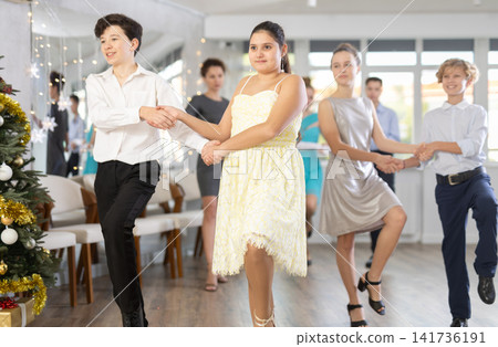 Teen boy and girl dancing modern discofox in couple during lesson at studio in New Year atmosphere Teen boy and girl dancing modern discofox in couple during lesson at studio in New Year atmosphere 141736191