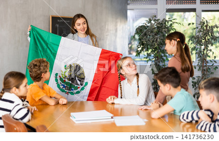 Teacher showing Mexico flag to group of schoolchildren Teacher showing Mexico flag to group of schoolchildren 141736230