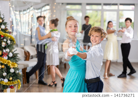 Teen boy and girl dancing waltz in couple during lesson at studio in New Year atmosphere Teen boy and girl dancing waltz in couple during lesson at studio in New Year atmosphere 141736271