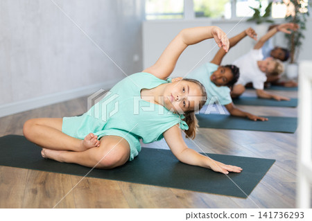 Young girl doing yoga in group of children Young girl doing yoga in group of children 141736293