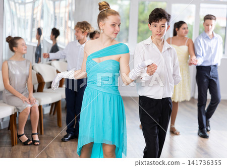 Positive teen boy and girl are dancing classic version of waltz in couple during lesson at studio Positive teen boy and girl are dancing classic version of waltz in couple during lesson at studio 141736355