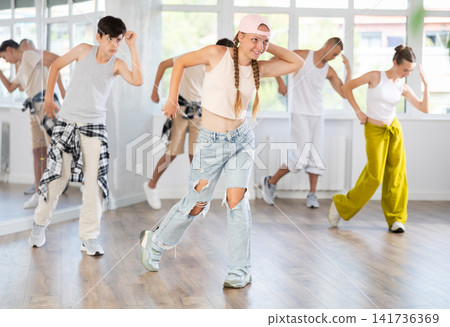 Teenage girl practicing hip hop slide moves in training hall Teenage girl practicing hip hop slide moves in training hall 141736369