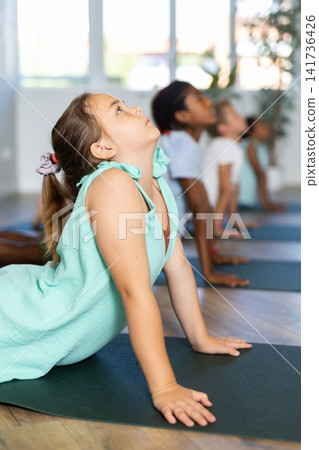 In sport studio with group of friends girl stand perform dog muzzle up, Urdhva Mukha Shvanasana In sport studio with group of friends girl stand perform dog muzzle up, Urdhva Mukha Shvanasana 141736426