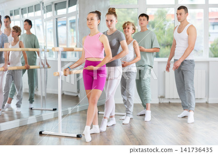 Teenage boys and girls practicing battement tendu position of ballet in dancehall Teenage boys and girls practicing battement tendu position of ballet in dancehall 141736435