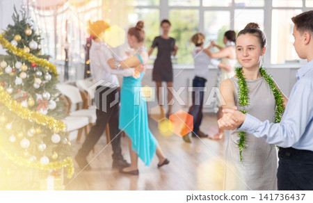 Teen boy and girl dancing waltz in couple during lesson at studio in New Year atmosphere Teen boy and girl dancing waltz in couple during lesson at studio in New Year atmosphere 141736437