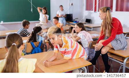 Schoolboy communicating with girl classmate at recess in class Schoolboy communicating with girl classmate at recess in class 141736457