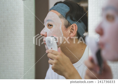 四十多歲男士的美容秘訣:將面膜和 LED 臉部護理儀結合起來照顧臉頰。 四十多歲男士的美容秘訣:將面膜和 LED 臉部護理儀結合起來照顧臉頰。 141736833