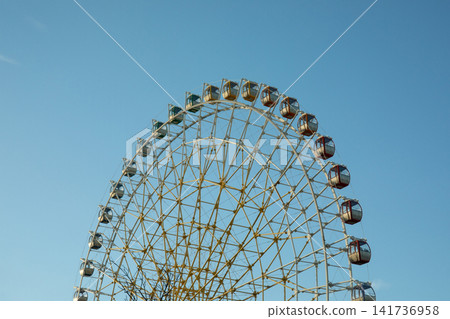 Ferris wheel stands tall, showcasing vibrant gondolas and bright colors 141736958